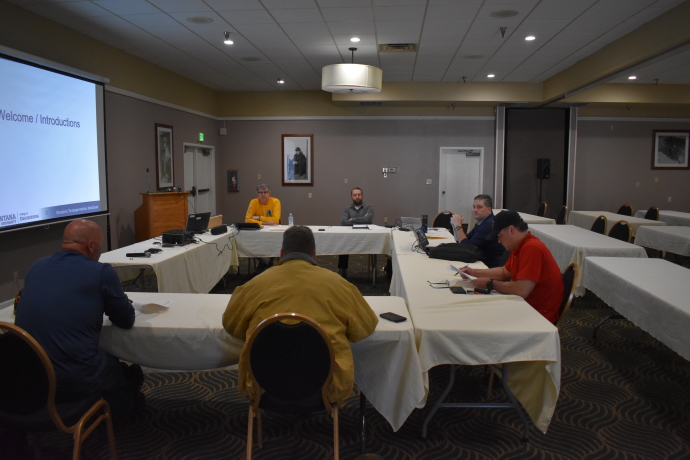 Six people sitting around tables arranged in a u shape.