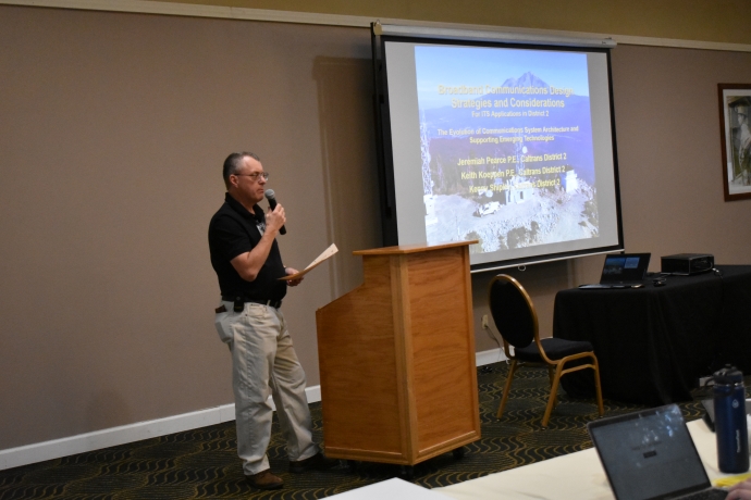 A man holds a microphone and presents to an audience.