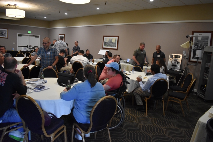 Groups of people talk to one another while seated at tables.