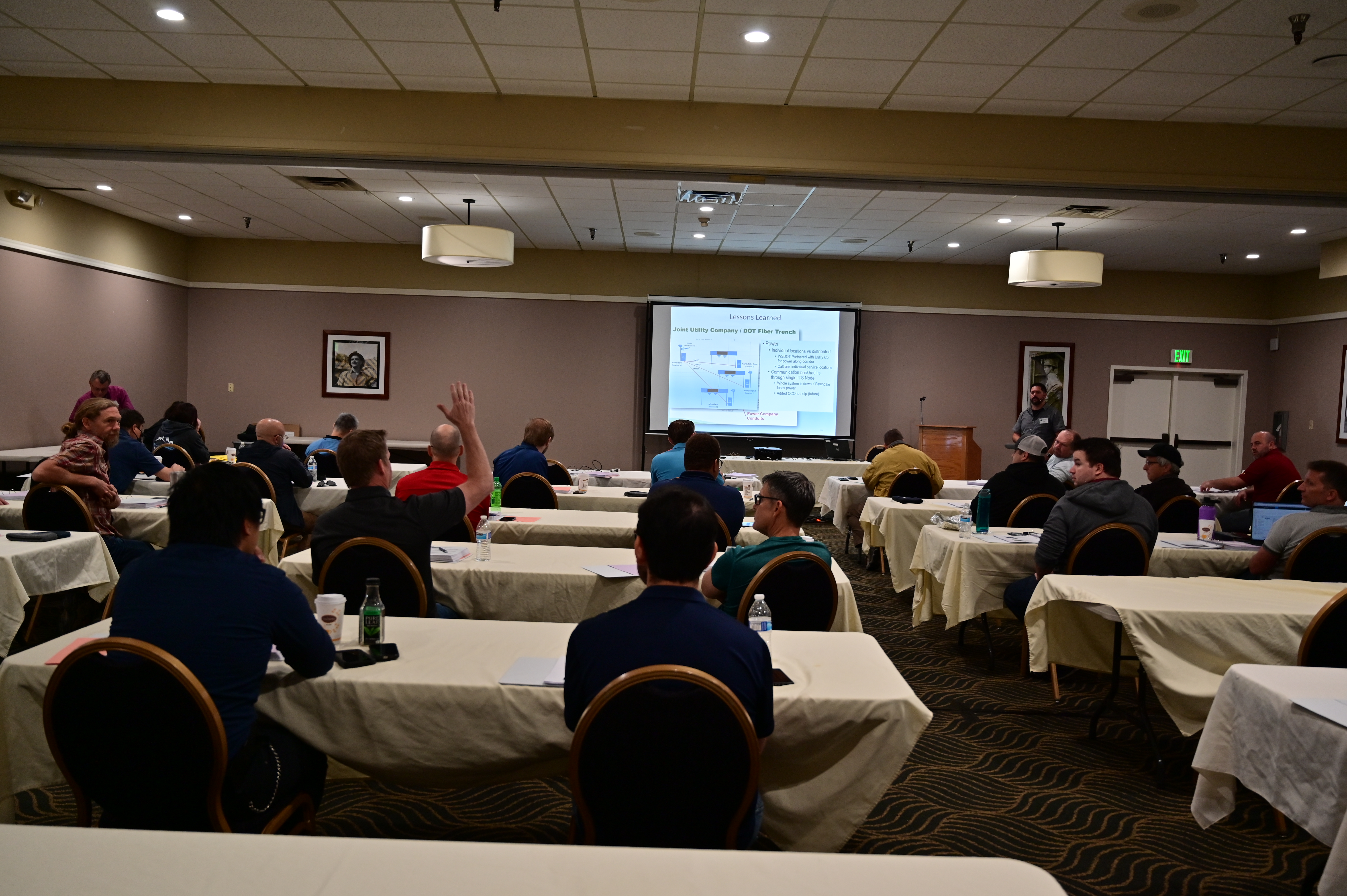 A man raises his hand while watching a presentation.